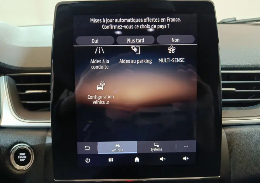 Écran tactile central du tableau de bord du Renault Captur rouge 2024 affichant les options d'aide à la conduite et configuration véhicule.