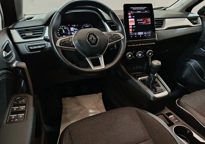 Intérieur noir du Renault Captur 2024 techno TCe 90, vue depuis le siège conducteur sur volant et écran tactile central vertical.