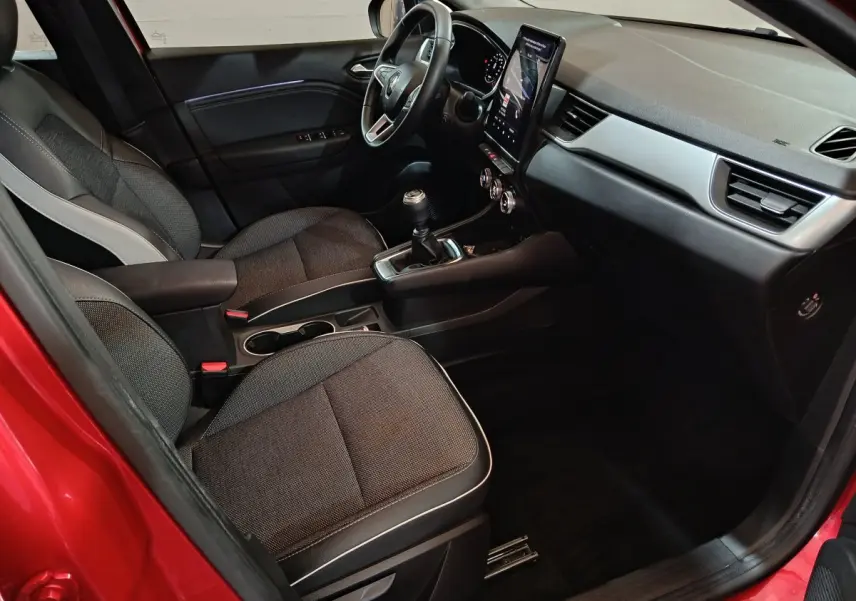Intérieur du Renault Captur rouge 2024, vue côté conducteur, avec tableau de bord moderne et boîte manuelle.