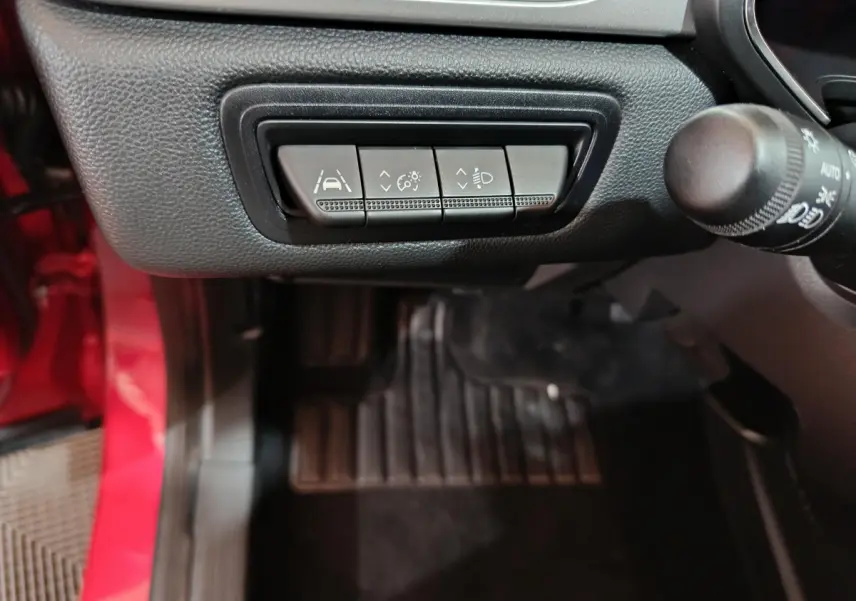 Gros plan sur les commandes d'assistance à la conduite du tableau de bord côté gauche d'un Renault Captur rouge 2024.