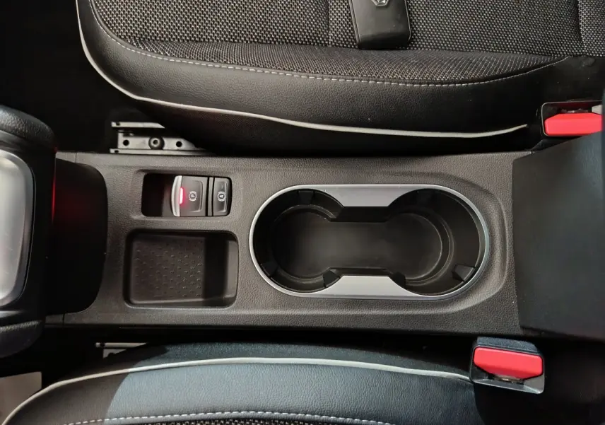Vue plongeante sur la console centrale noire du Renault Captur 2024, avec porte-gobelets et bouton frein à main électrique.
