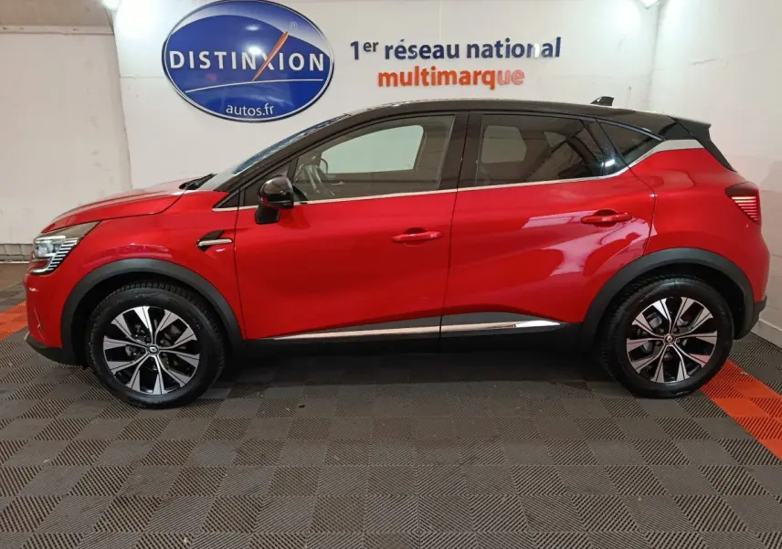 Vue latérale droite d'un Renault Captur Techno TCe 90 rouge avec toit noir et jantes alliage bicolores.