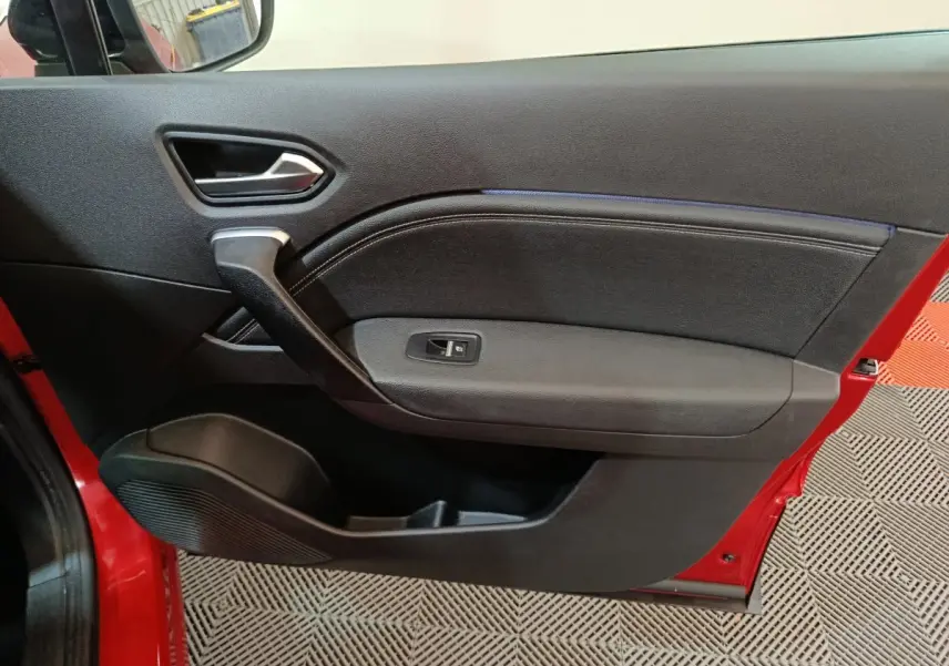 Gros plan sur la porte côté gauche rouge du Renault Captur 2024, avec poignée noire et commande de vitre électrique.