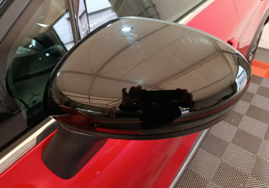 Rétroviseur droit noir brillant sur Renault Captur rouge 2024, vue rapprochée côté conducteur.