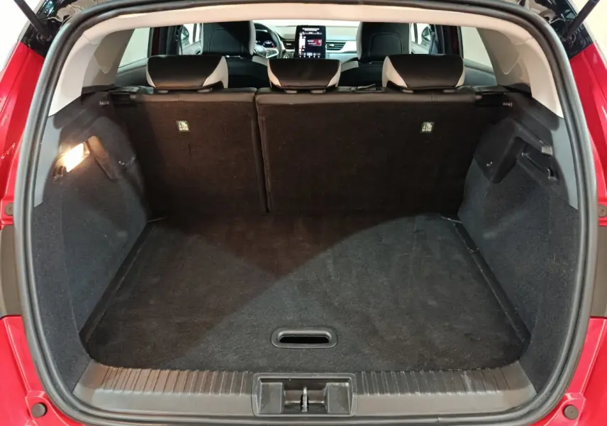 Coffre ouvert vu de l'arrière d'un Renault Captur rouge 2024, montrant l'espace de chargement et les sièges arrière.