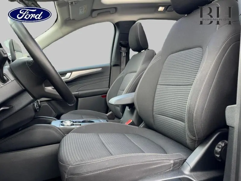 Vue intérieure côté conducteur du Ford Kuga 2022 avec sièges sport noirs et accoudoir central.