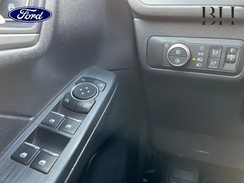 Gros plan sur les commandes de vitres et réglages des phares côté gauche intérieur du Ford Kuga Premium Rouge Lucid 2022.