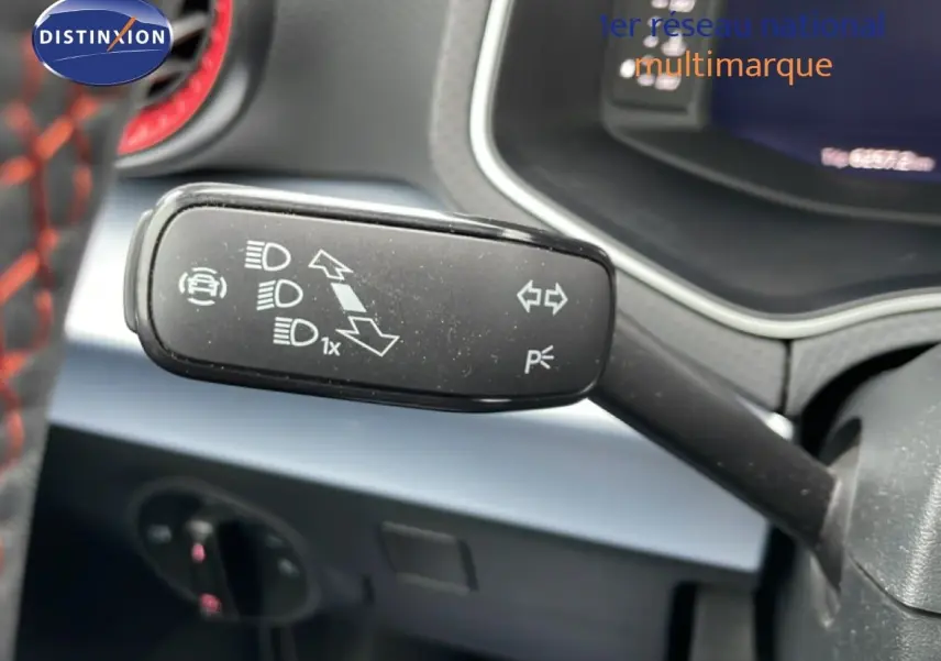 Gros plan sur la manette de clignotants et feux du tableau de bord d’un SEAT Arona bleu saphir métal avec toit blanc.