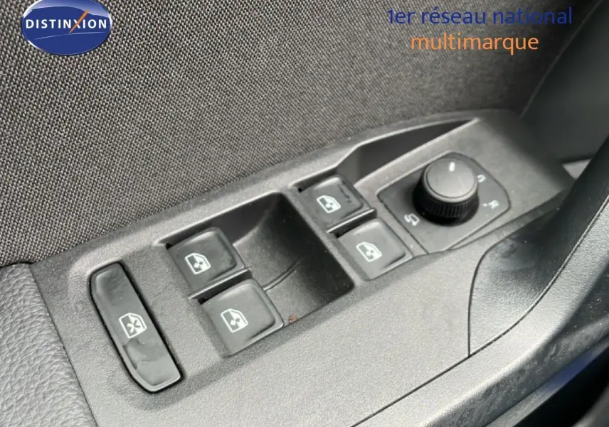 Gros plan sur les commandes des vitres électriques et rétroviseurs côté conducteur du SEAT Arona bleu saphir métal avec toit blanc.