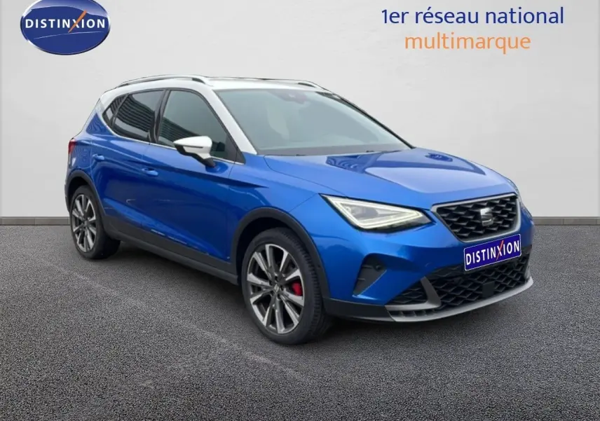 SEAT Arona bleu saphir métal avec toit blanc, vue 3/4 avant droit, jantes alliage et calandre noire distinctive.