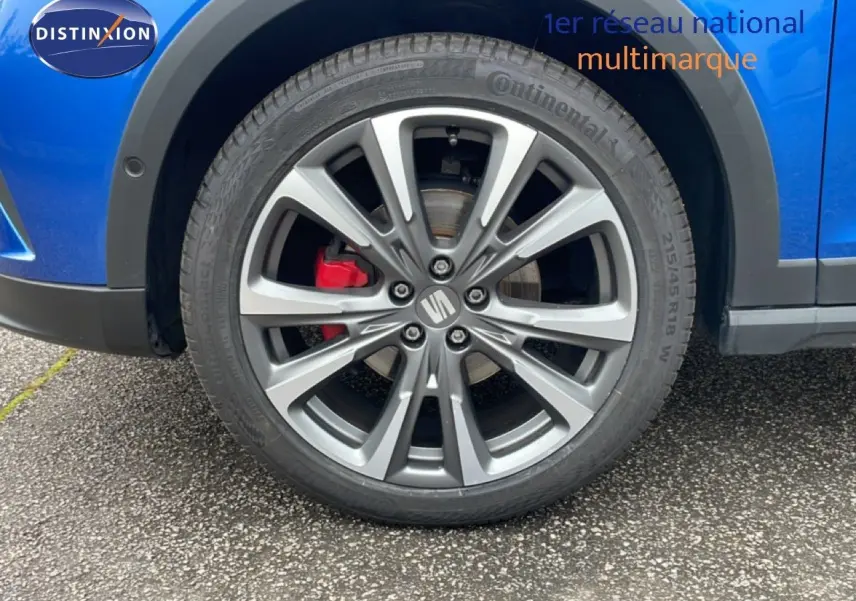 Gros plan sur la roue avant droite d'une SEAT Arona bleu saphir métal avec étrier de frein rouge.