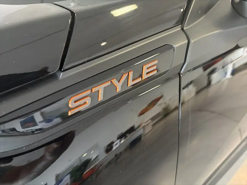 Gros plan sur l’inscription STYLE orange sur la porte côté gauche d’un Peugeot 2008 noir métal 2025.