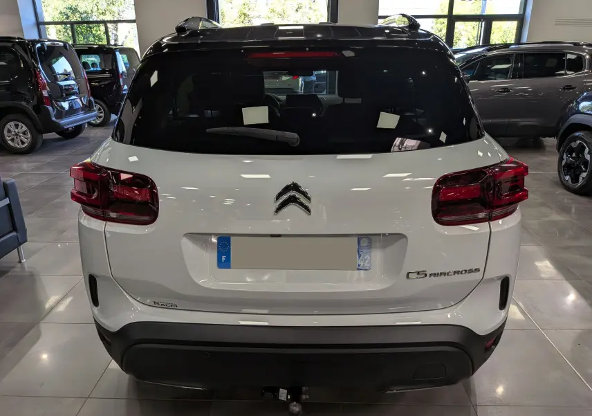 Vue arrière d'un Citroën C5 Aircross 2025 blanc Okénite avec toit noir, en intérieur de showroom.
