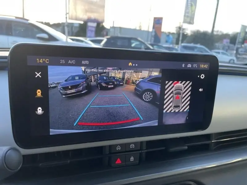 Écran intérieur montrant la caméra de recul avec vue arrière d’un parking, tableau de bord moderne de la Fiat 600 blanche 2025.