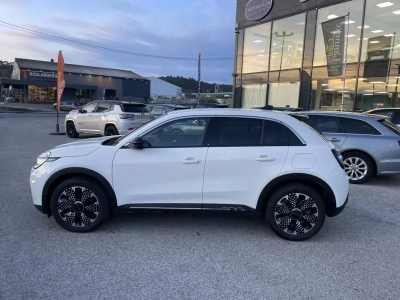 Vue de profil côté gauche d'une FIAT 600 blanche 1.2 Hybrid 100 cv La Prima DCT6 avec jantes noires distinctives.