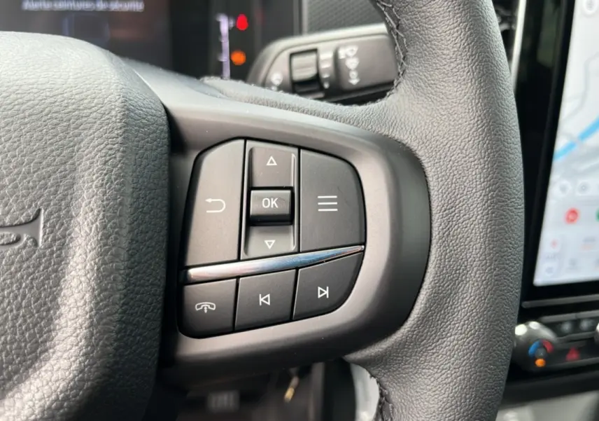 Gros plan sur les commandes multifonctions à droite du volant cuir noir du Ford Ranger gris carbone, avec écran tactile visible.
