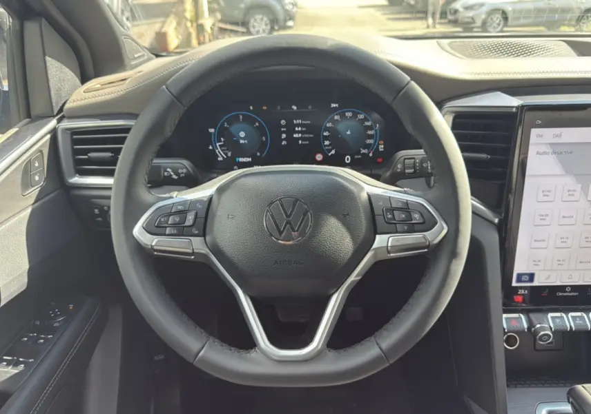 Vue intérieure centrée sur le volant cuir multifonctions et le tableau de bord digital du Volkswagen Amarok gris foncé.