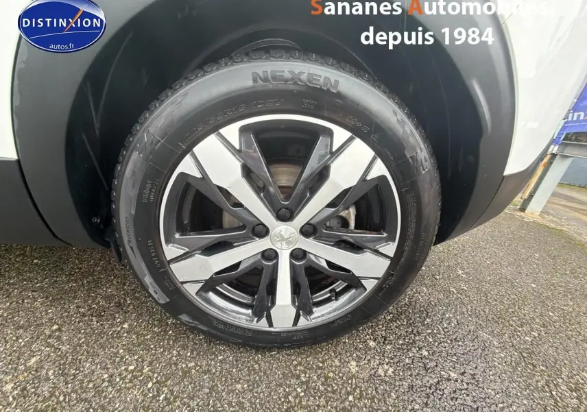 Gros plan sur la roue avant droite du Peugeot 3008 blanc nacré, mettant en valeur la jante alliage 18 pouces Los Angeles.