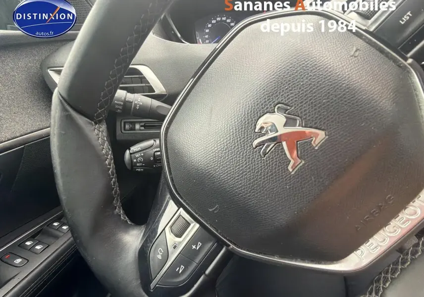 Gros plan sur le volant cuir noir avec logo Peugeot du Peugeot 3008 blanc, vue intérieure côté conducteur.