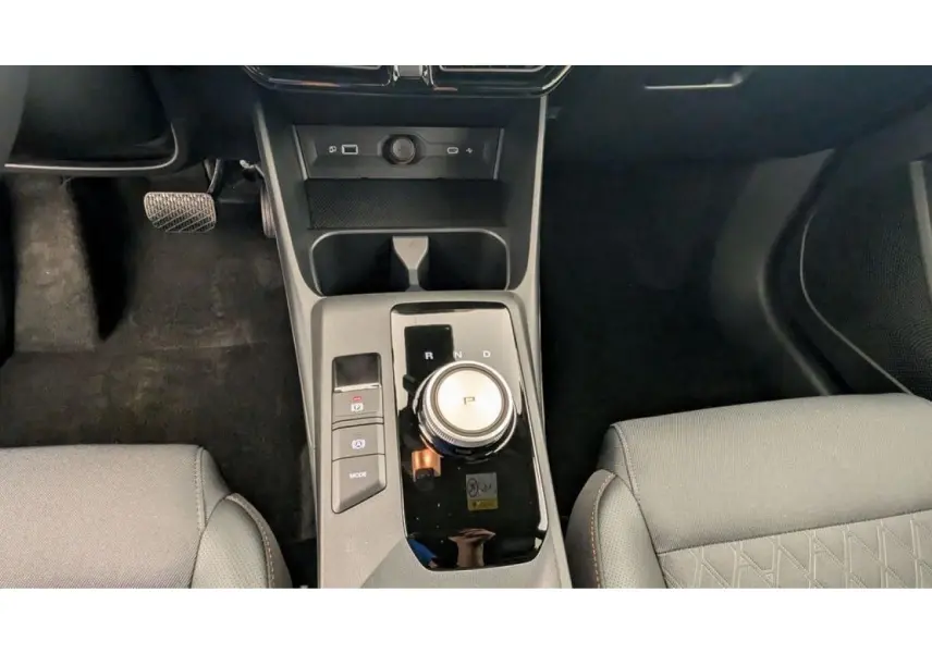 Vue intérieure centrée sur la console centrale avec molette de boîte auto et sièges tissu/similicuir gris clair.