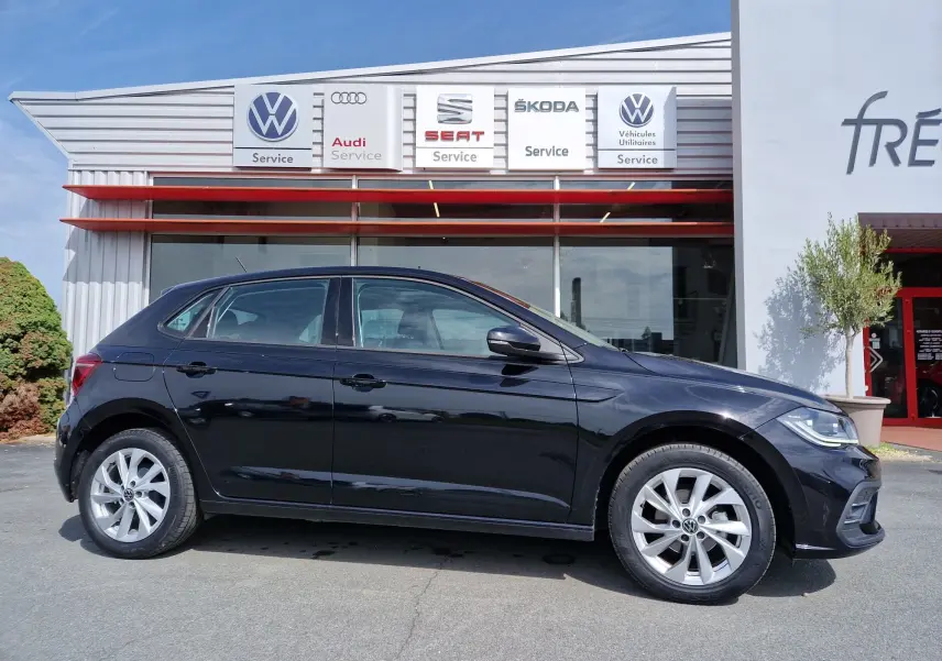 Profil latéral droit d'une Volkswagen Polo noire de 2022, garée devant un service multimarques.