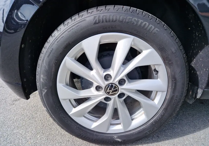 Gros plan sur la roue avant gauche d'une Volkswagen Polo noire avec jante argentée et pneu Bridgestone.