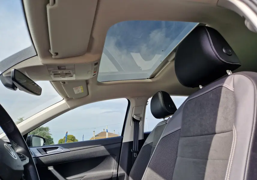 Vue intérieure côté conducteur d'une Volkswagen Polo noire 2022 avec toit panoramique et sièges en tissu gris.