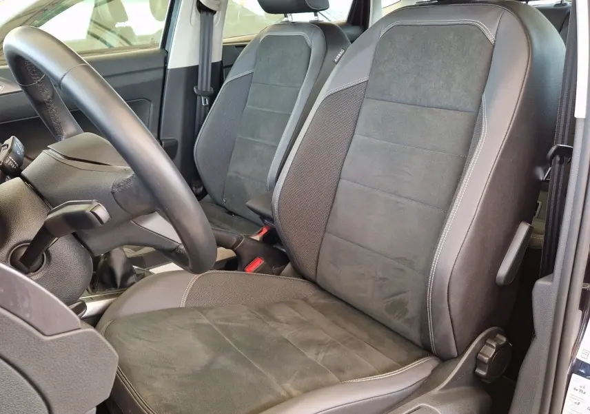 Vue intérieure côté conducteur d'une Volkswagen Polo noire 2022, sièges en tissu et cuir noir avec toit ouvrant.