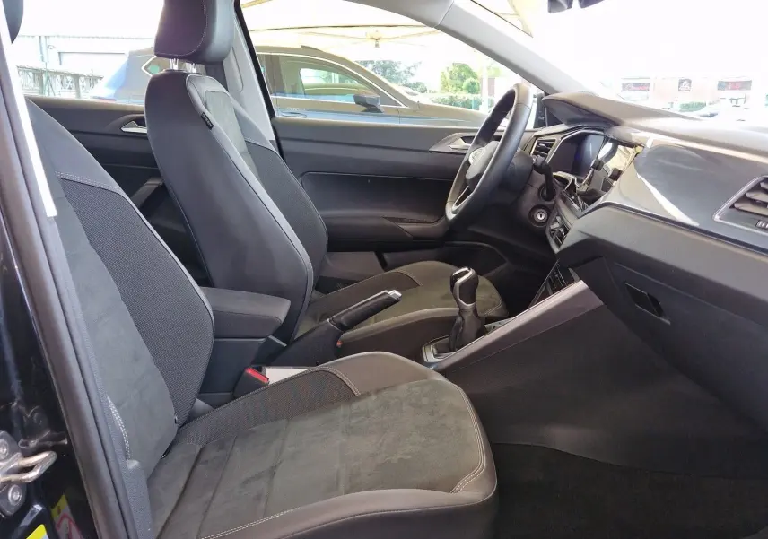 Intérieur côté conducteur d'une Volkswagen Polo noire 2022, sièges tissu noir et toit ouvrant panoramique visible.