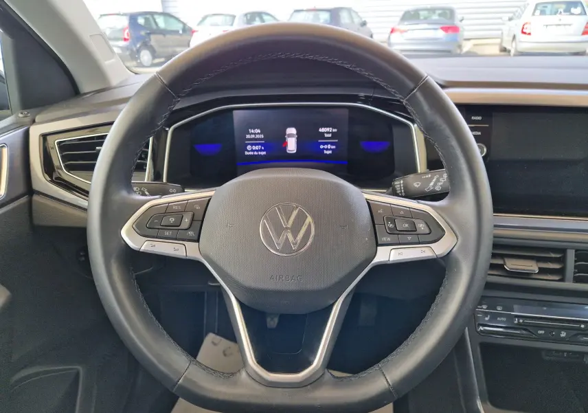Vue intérieure centrée sur le volant noir multifonction d'une Volkswagen Polo 2022 avec tableau de bord digital allumé.