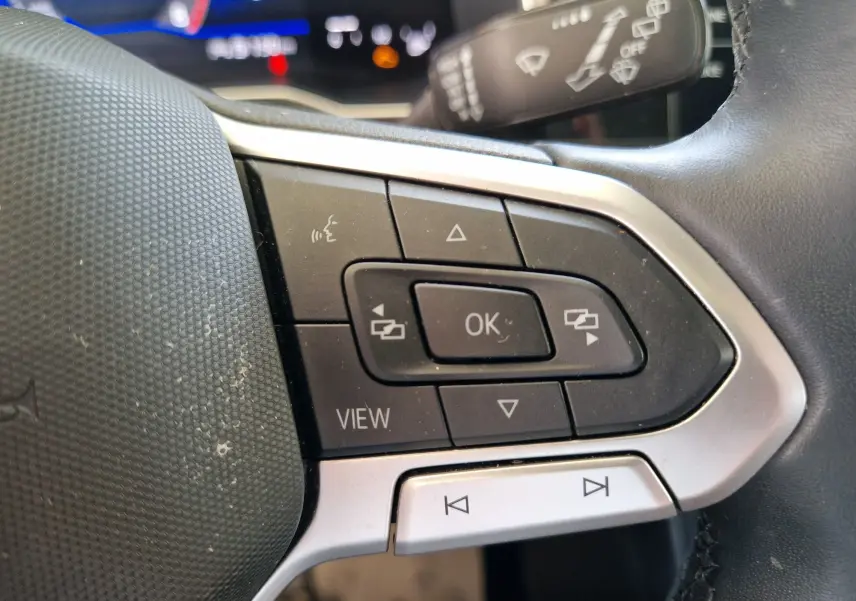 Gros plan sur les commandes au volant côté gauche de la Volkswagen Polo noire 2022 avec boutons multifonctions et affichage numérique.