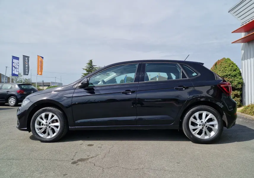 Profil côté gauche d'une Volkswagen Polo noire 2022 avec jantes alliage et vitres teintées, stationnée en extérieur.
