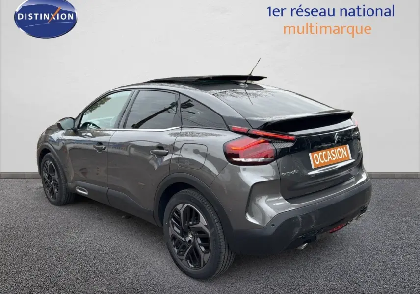 Citroën C4 gris avec toit noir en 3/4 arrière droit, mettant en valeur son design moderne et ses feux arrière distinctifs.
