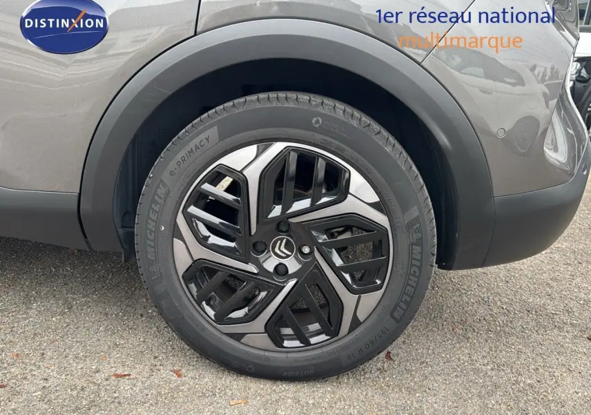 Gros plan sur la roue arrière droite d'une Citroën C4 gris avec jante noire et argentée au design moderne.