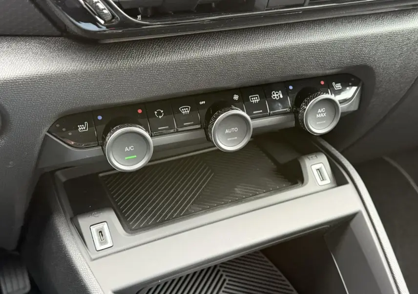 Commandes de climatisation automatique et ports USB dans l'habitacle noir de la Citroën C4 hybride 2025.