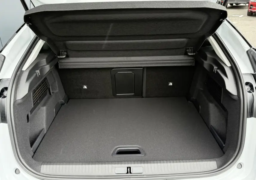 Coffre ouvert vu de l'arrière d'une Citroën C4 hybride blanc Okénite avec intérieur noir et toit Perla Nera.