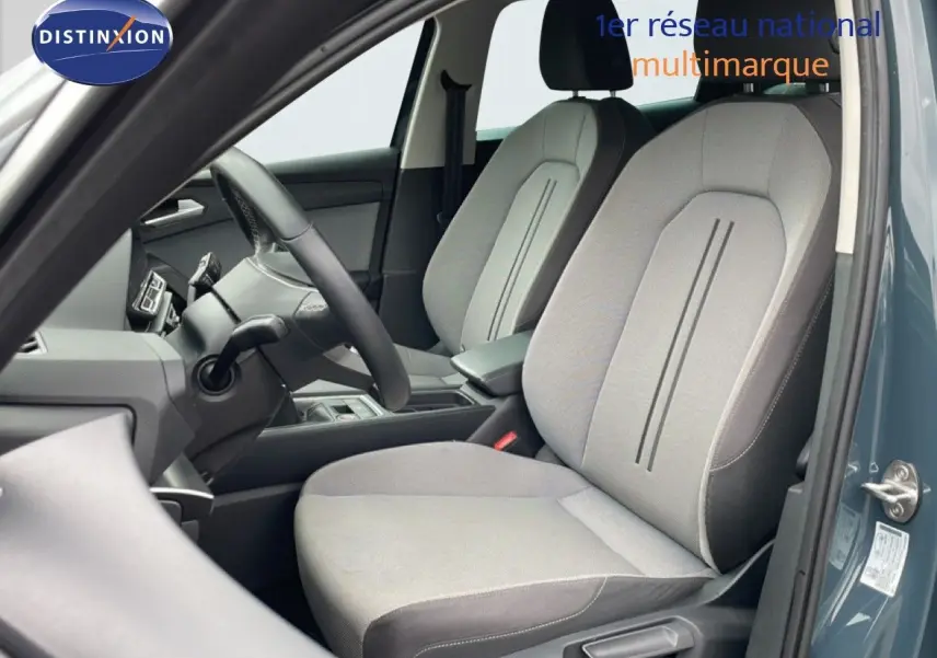 Vue intérieure côté conducteur du SEAT LEON ST 2025 gris magnétique, montrant les sièges en tissu clair et le volant multifonction.