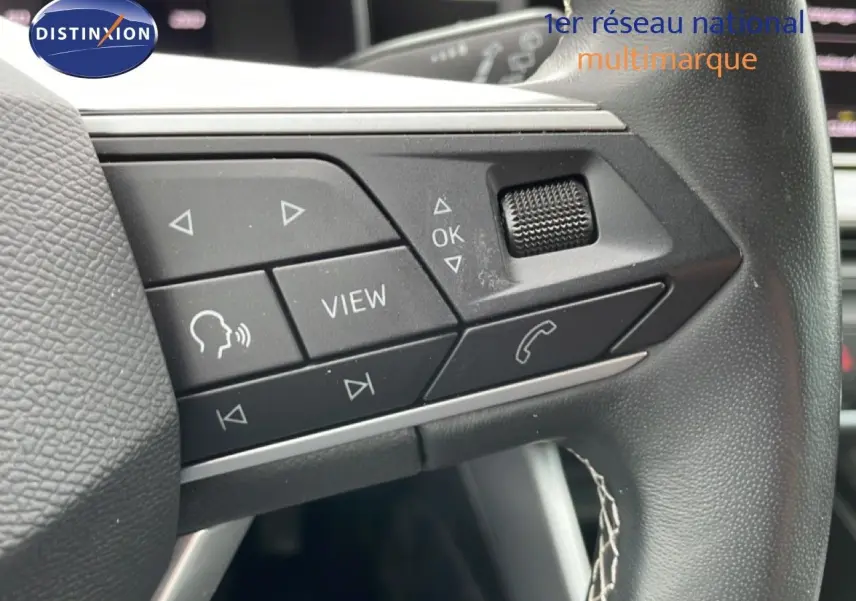 Gros plan sur les commandes au volant en cuir noir du SEAT LEON ST 2.0 TDI 115CH STYLE XL, intérieur moderne.