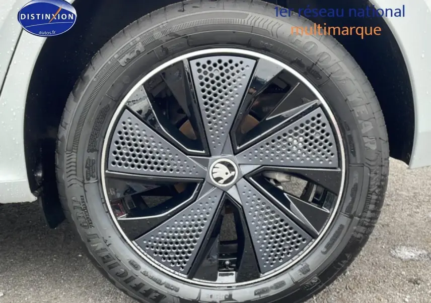 Gros plan sur la jante noire et grise du Skoda Kamiq blanc nacré, mettant en valeur son design moderne perforé.