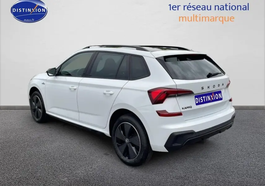 Vue 3/4 arrière droite d'un Skoda Kamiq blanc nacré avec jantes noires et toit panoramique en verre.