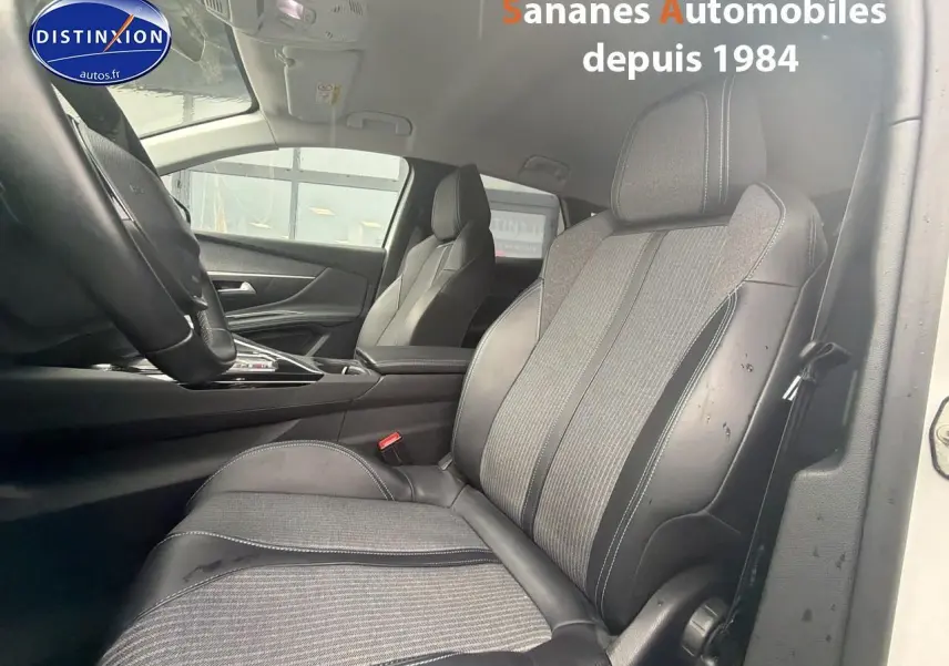 Vue intérieure côté conducteur du Peugeot 3008 Hybrid 225 blanc, mettant en valeur les sièges en cuir et tissu gris.