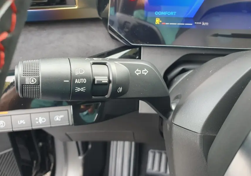 Gros plan sur la commande des feux et clignotants à gauche du volant dans le tableau de bord numérique de la Renault Clio VI noire étoile.