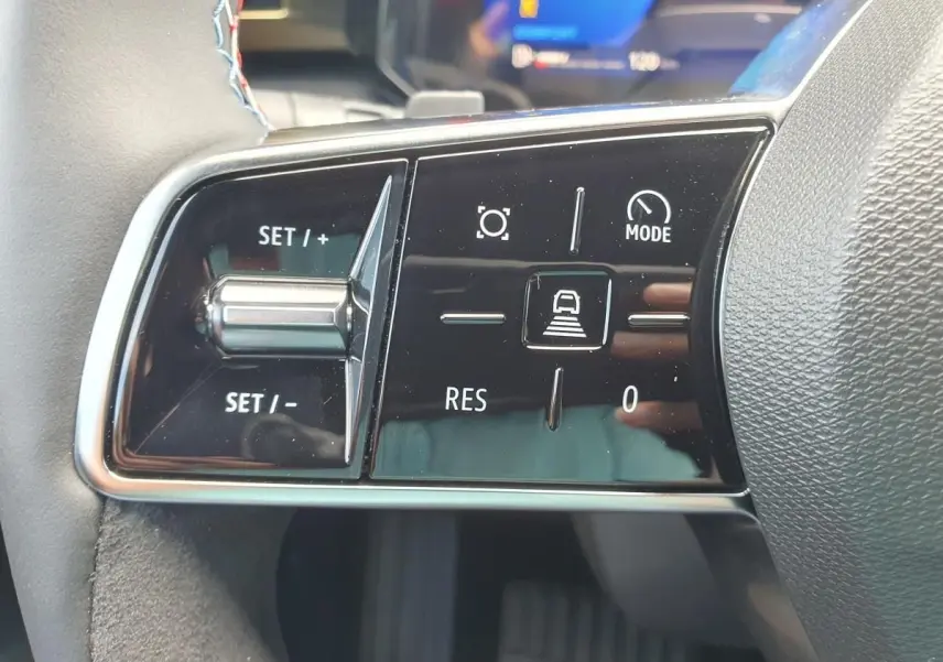 Gros plan sur les commandes de régulateur de vitesse au volant de la Renault Clio VI noire étoile, intérieur moderne.