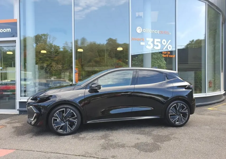 Profil droit d’une Renault Clio VI noire étoile avec jantes alliage diamantées 18” cosmic, stationnée devant une vitrine.