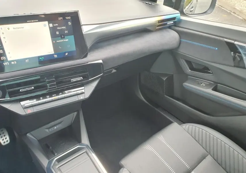 Intérieur avant droit de la Renault Clio VI noire étoile, avec écran tactile et surpiqûres bleues sur la portière.