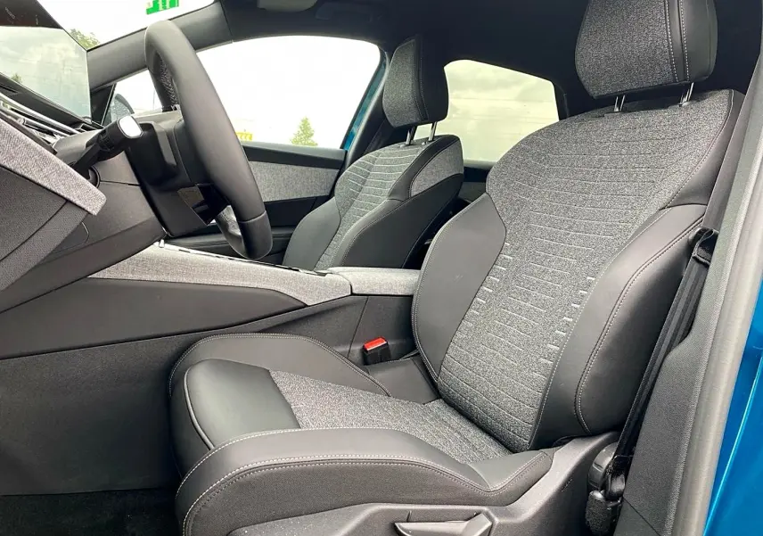 Vue intérieure côté conducteur du Peugeot 3008 bleu obsession, mettant en valeur les sièges bi-matière gris et noir avec coutures contrastées.