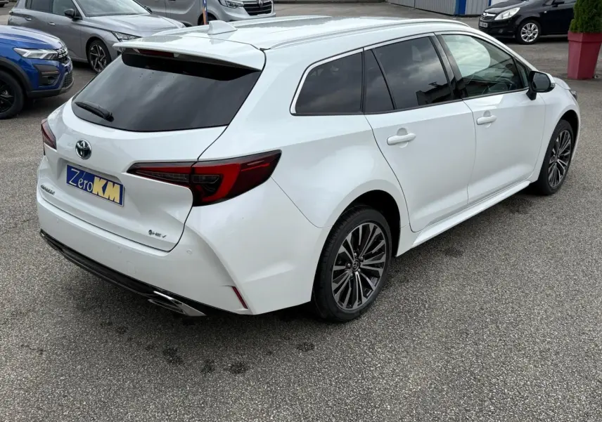 Toyota Corolla Touring Sport blanc lunaire nacré vue 3/4 arrière droit avec jantes alliage et vitres teintées.