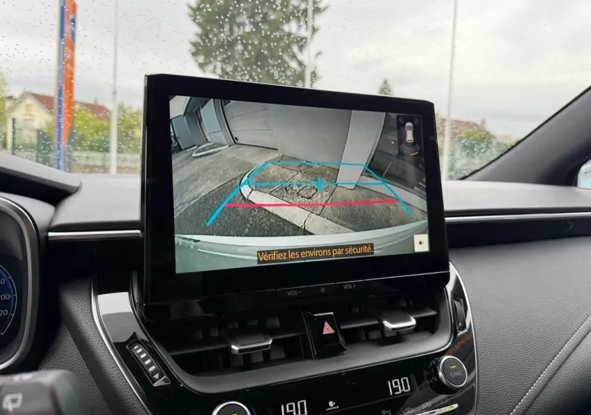 Écran central de la Toyota Corolla Touring Sport 2025 affichant la caméra de recul avec vue arrière et consignes de sécurité.