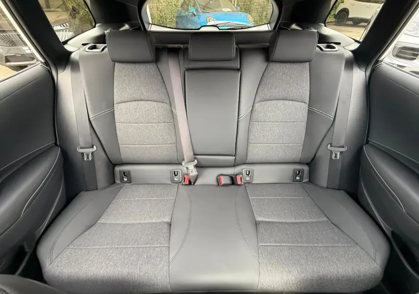 Banquette arrière en tissu gris et cuir noir de la Toyota Corolla Touring Sport 2025 vue de face, avec ceintures et appuie-têtes.