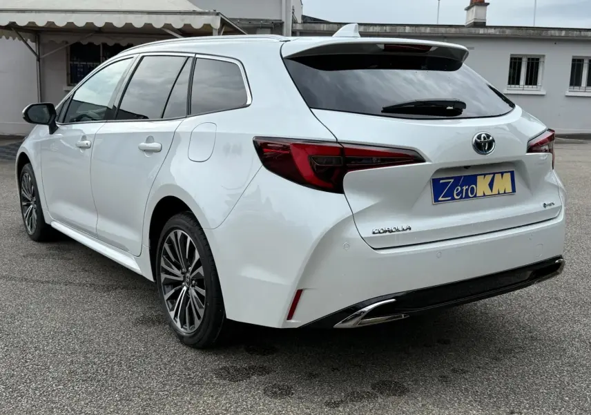 Toyota Corolla Touring Sport blanc lunaire nacré vue 3/4 arrière droit avec feux LED et jantes alliage.